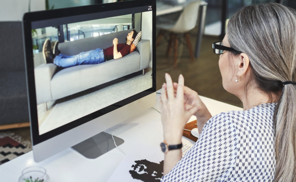 A man on a couch with a therapist giving a virtual therapy session
